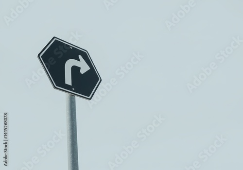 Obraz na płótnie A black hexagonal direction sign showing a white right turn arrow against a pale sky. Road safety concept and travel planning for traffic guidance. w salonie