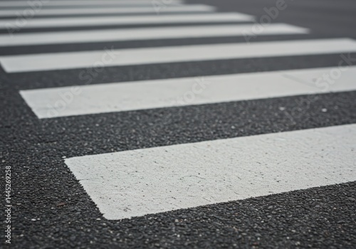 Obraz na płótnie Surface level view of a asphalt road with white, painted pedestrian crosswalk stripes. Road safety concept for transport background or traffic awareness. w salonie