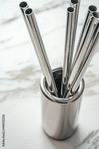 A polished reusable straws in a sleek metal holder, set on a clean marble surface