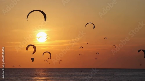 Kiteboarding silhouettes at sunset over water.