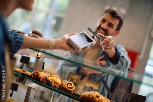 Fotografía Close up of bakery customer paying with smart phone app.