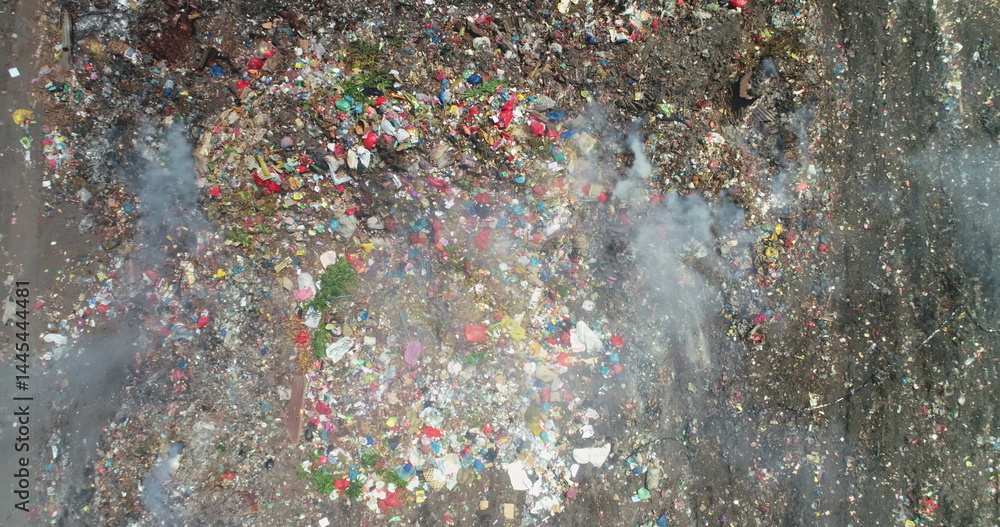 Aerial view of a smoking garbage dump with plastic waste causing air pollution in Ende, Flores island, Indonesia, highlighting environmental damage and waste management issues