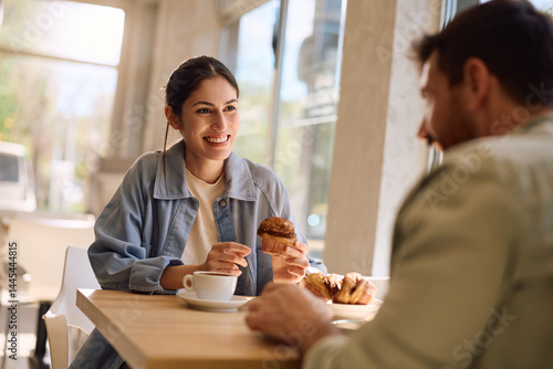 Schilderij op canvas Happy woman talking to her boyfriend while eating cupcake at bakery shop