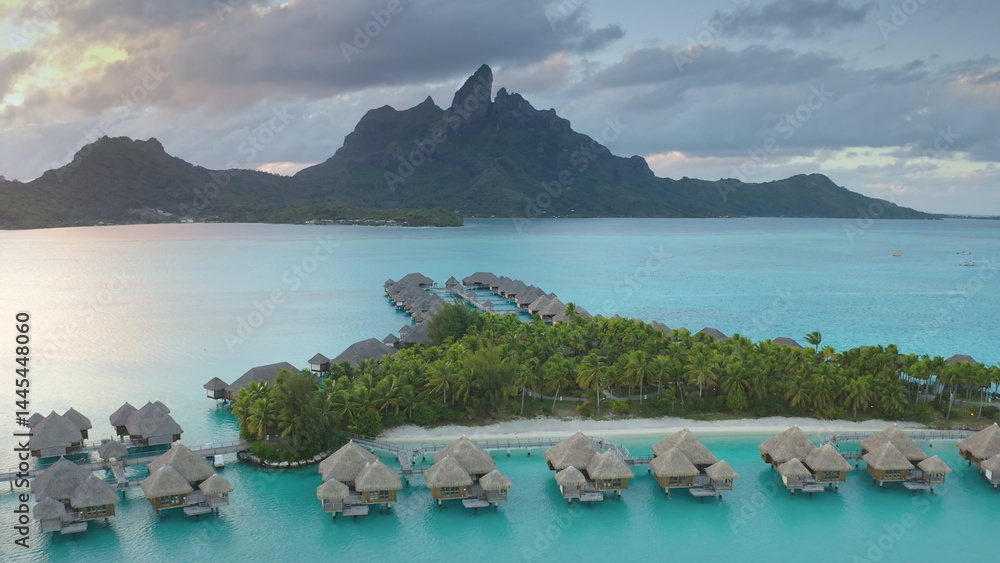 Drone fly over turquoise water lagoon and overwater bungalows resort, mount Otemanu in Bora Bora, French Polynesia. Popular travel destination, remote wild paradise, exotic summer travel. Aerial view