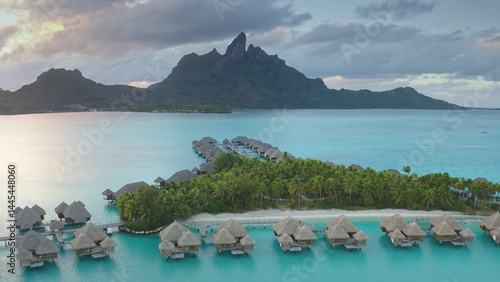 Obraz na płótnie Drone fly over turquoise water lagoon and overwater bungalows resort, mount Otemanu in Bora Bora, French Polynesia. Popular travel destination, remote wild paradise, exotic summer travel. Aerial view w salonie