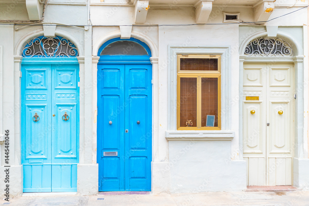 Facade of a residential building with three locked wooden doors painted in light blue, blue and white color