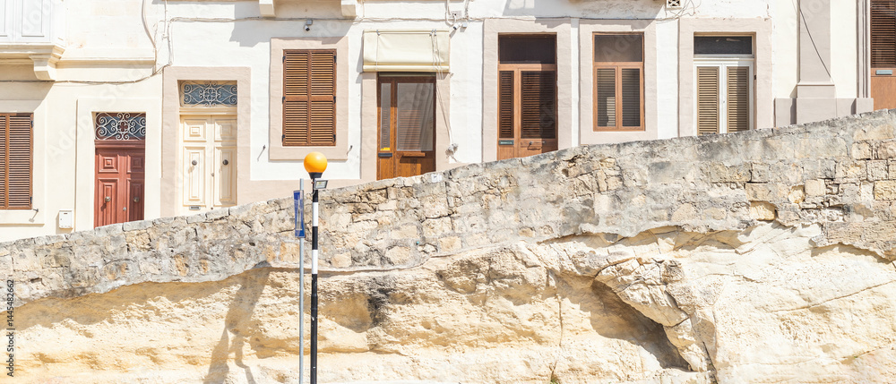 Wide image showing multiple entrance doors and windows of a residential building in Malta