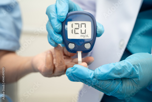 Fotografie Asian doctor using digital glucose meter for check sample blood sugar level to treatment diabetes