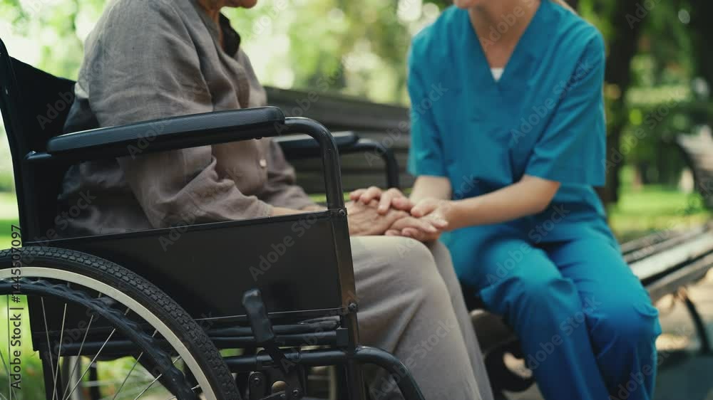 Nurse supporting and talking with sad elderly patient in wheelchair, comfort Nurse supporting and talking with sad elderly patient in wheelchair, comfort