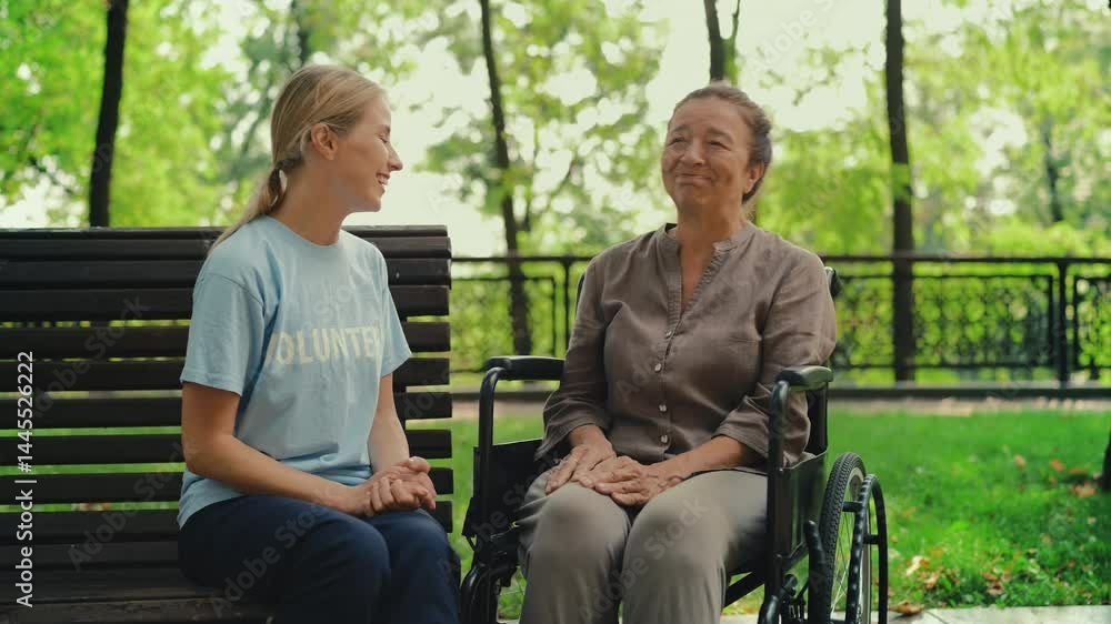 Kind volunteer speaking with senior wheelchair user in park, offering assistance Kind volunteer speaking with senior wheelchair user in park, offering assistance