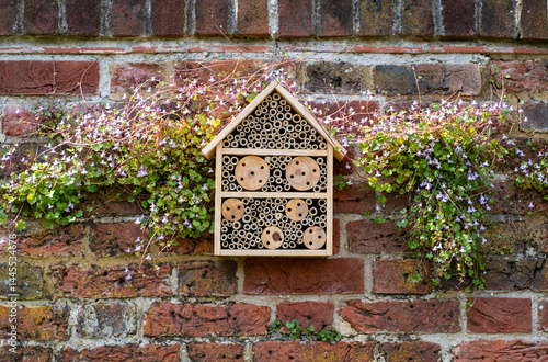 Foto Bug house hotel for insects, surrounded by flowers, affixed to the wall at Eastcote House Gardens, in Hillingdon London UK