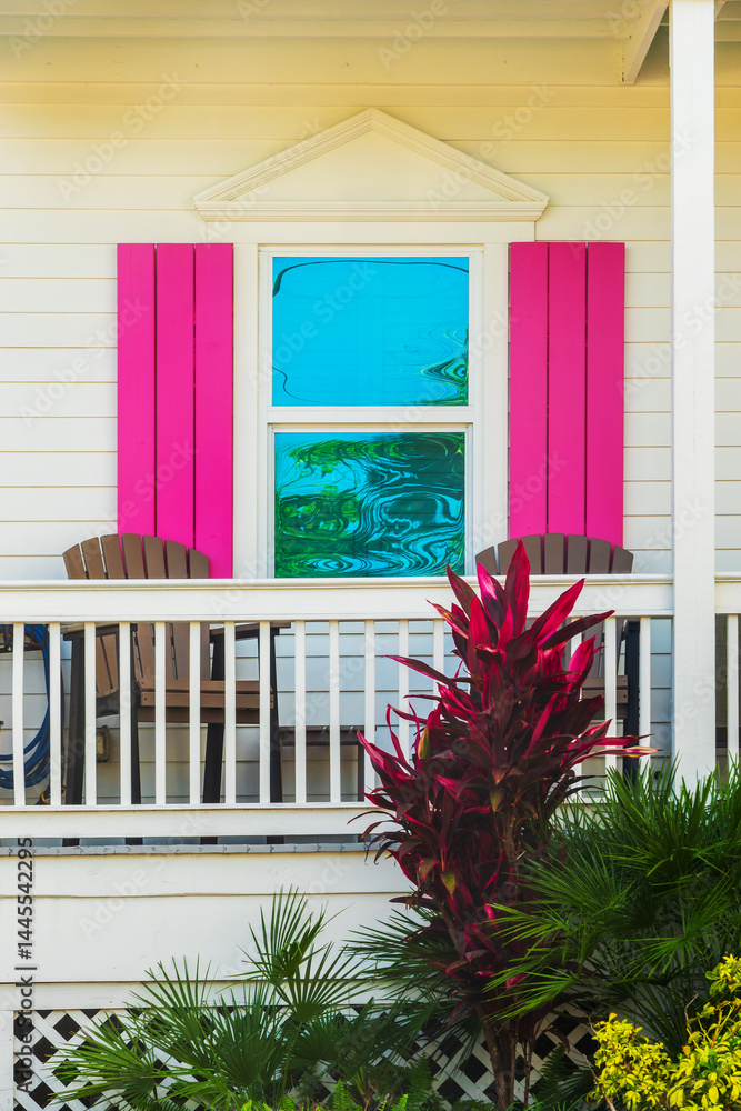 Window of a wooden house with pink shutters, colorful architecture in Bahama village, Key West, Florida