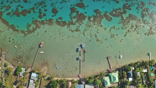 Fotografie Turquoise water coral reef and tropical island coastline, wooden pier stretching to crystal clear shallows of pristine paradise
