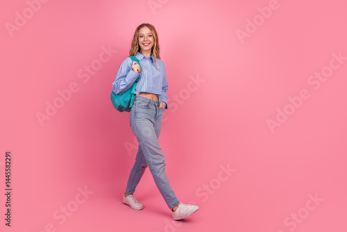 Obraz na płótnie Smiling young woman in stylish attire walking confidently with her backpack against a vibrant pink background w salonie