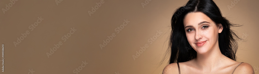 Banner with beauty studio portrait of young beautiful smiling woman with black loose waving hair against beige background