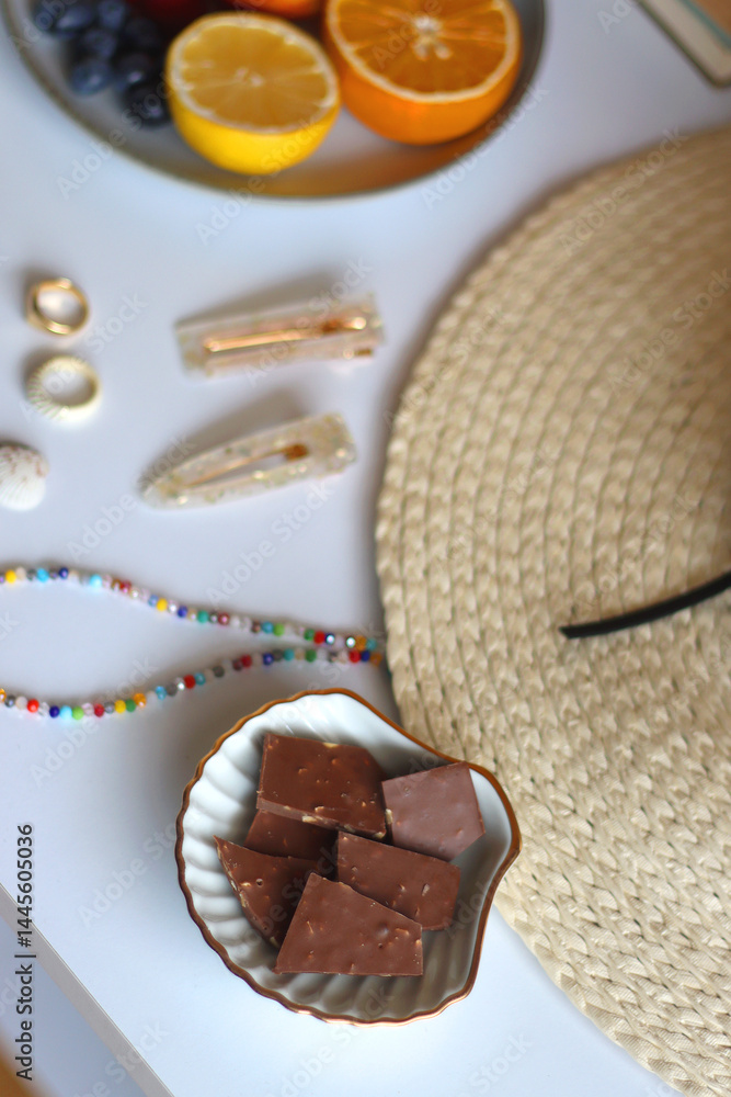 Glass of cocktail, straw hat, sunglasses, books, fresh fruit, chocolate and accessories. Summer essentials on the table. Selective focus.