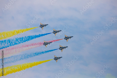 Six fighter jets fly in formation leaving colorful smoke trails across a clear blue sky.
