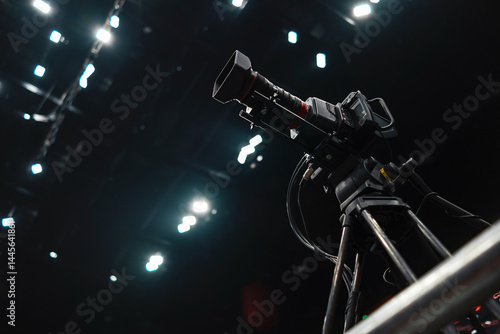 Professional camera stands on a tower on a tripod in a concert hall