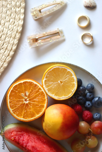 Glass of cocktail, straw hat, sunglasses, books, fresh fruit, chocolate and accessories. Summer essentials on the table. Top view.