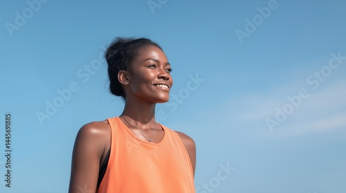 Obraz na płótnie Smiling woman in athletic wear enjoys a sunny day outdoors, showcasing confidence and fitness while looking towards the horizon. w salonie