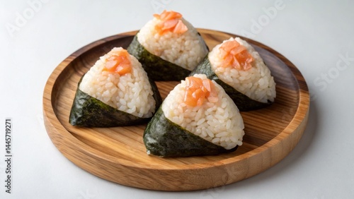 Obraz na płótnie Four triangular onigiri are arranged on a circular wooden plate, topped with pieces of salmon. The rice is perfectly molded and wrapped in seaweed, creating an appetizing display w salonie