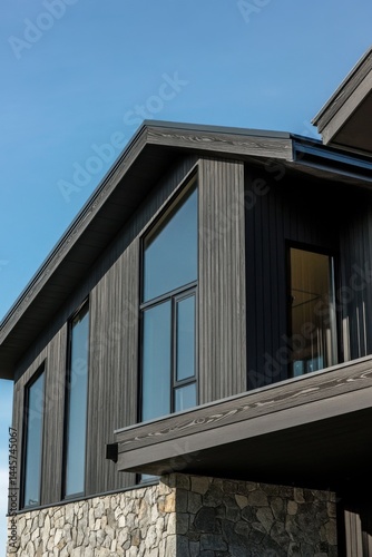 Wallpaper Mural Modern architectural design of a dark wood and stone house under clear blue sky during daytime with expansive windows showcasing a contemporary style Torontodigital.ca