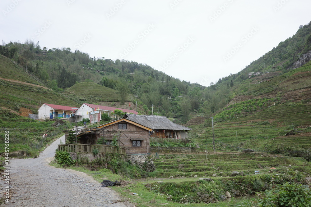 Rustic wooden house and terraced fields nestled in a peaceful valley in Sapa, Vietnam. Surrounded by lush hills and a quiet path, this scene reflects authentic rural life and traditional mountain. Rustic wooden house and terraced fields nestled in a peaceful valley in Sapa, Vietnam. Surrounded by lush hills and a quiet path, this scene reflects authentic rural life and traditional mountain.