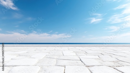 Empty white stone pavement terrace overlooking the calm blue sea under a bright sunny sky.