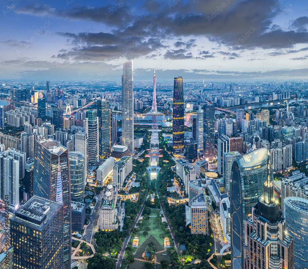 Fototapeta premium Panoramic view of the illuminated modern city financial district skyline with tall towers at dusk in Guangzhou, China.