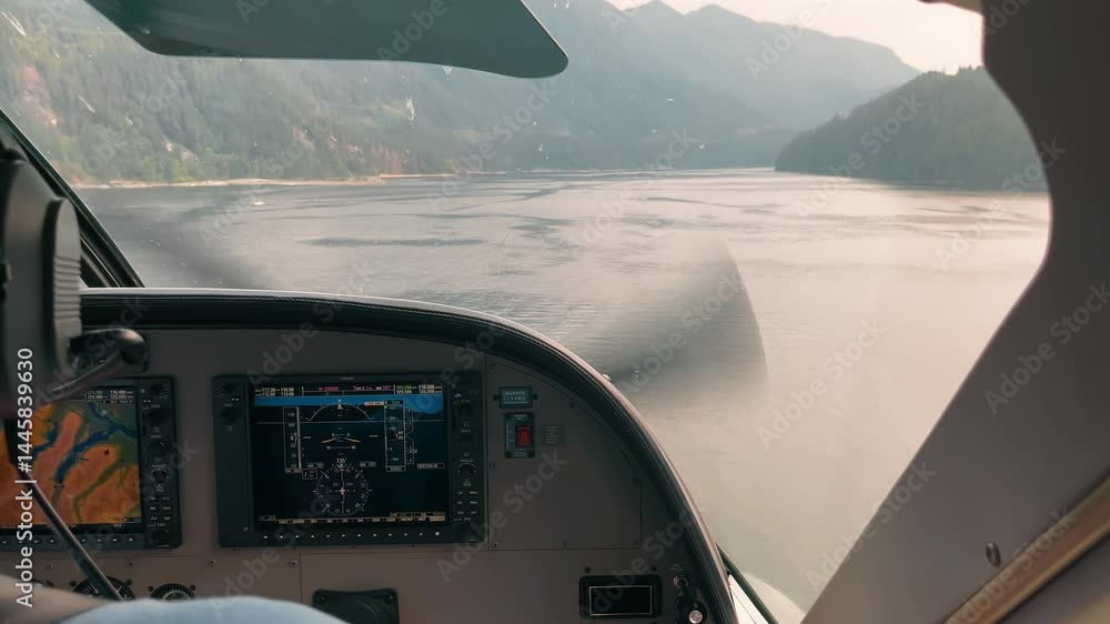 Cockpit view of small aircraft flying over calm mountain lake, digital instruments and scenic landscape ahead Cockpit view of small aircraft flying over calm mountain lake, digital instruments and scenic landscape ahead