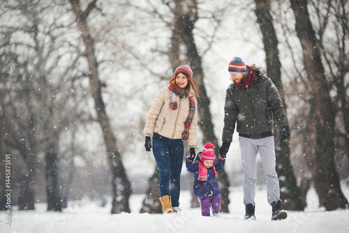 Young family with baby girl having fun in the snow
