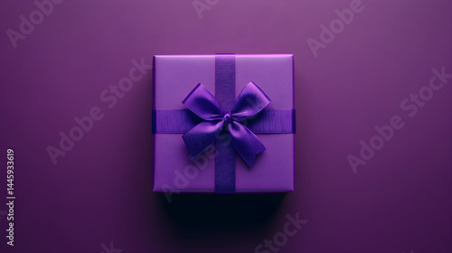 Purple gift box with satin ribbon and bow on monochromatic purple background