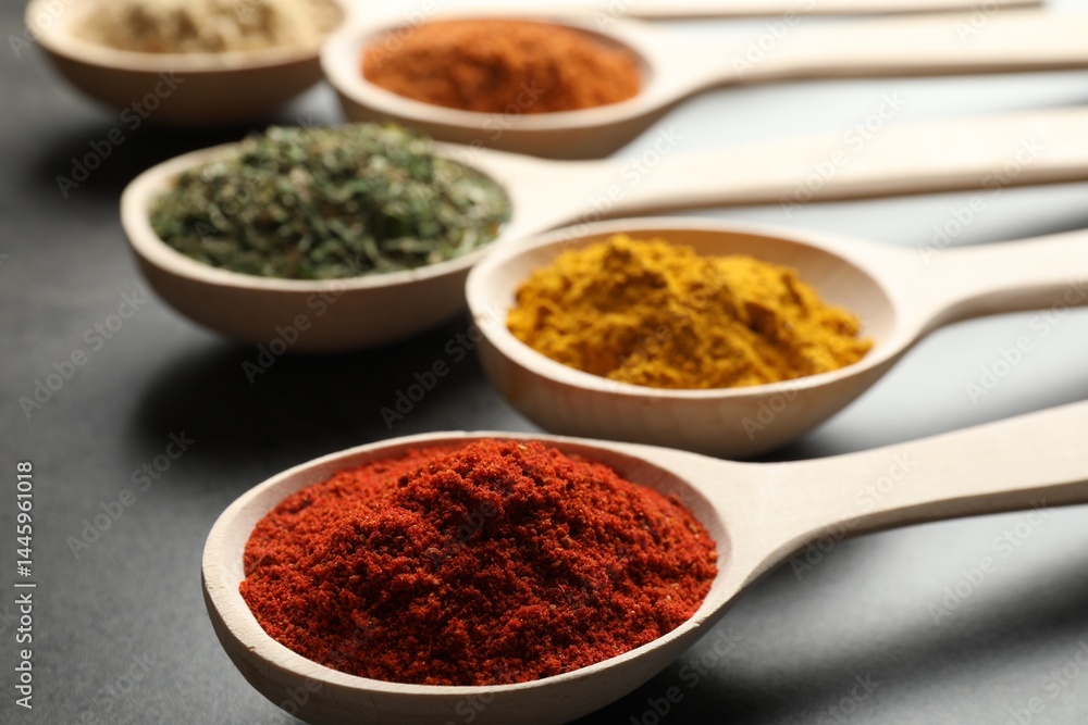 Many different spices in spoons on grey table, closeup Many different spices in spoons on grey table, closeup