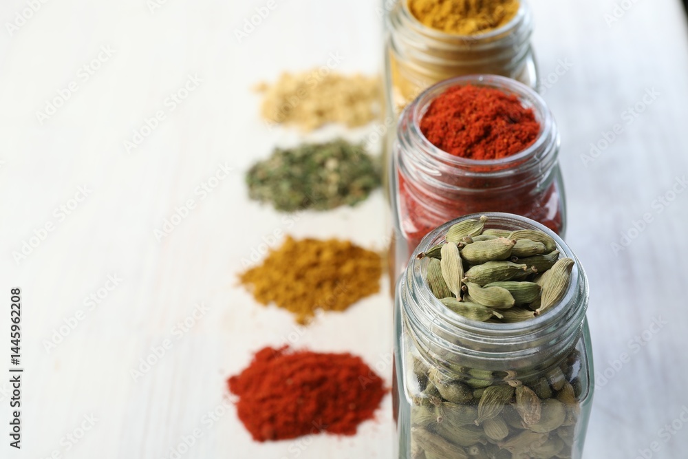 Different aromatic spices in jars on white table, closeup. Space for text Different aromatic spices in jars on white table, closeup. Space for text