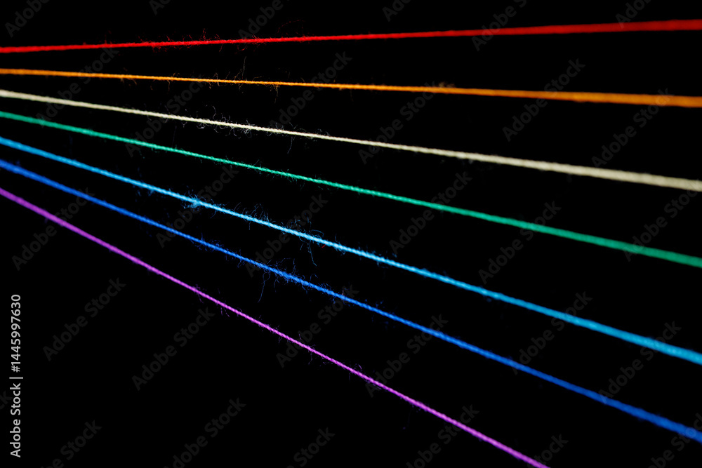 multicolored sewing threads in the form of a rainbow on a black background
