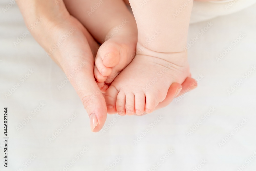 mom's hand holds the baby's little foot on the white background of the bed, mom's love and tenderness mom's hand holds the baby's little foot on the white background of the bed, mom's love and tenderness