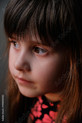 Softly lit portrait focusing on the child's delicate features and side view. Calm and peaceful image of a child lost in her own thoughts.