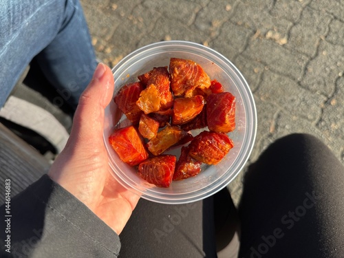 Fresh local Maple syrup glazed Candy Salmon Nuggets prepacked plastic bowls for takeaway enjoyed outside held in hand