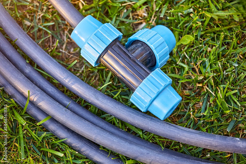 Fittings pipes and connectors for the garden and lawn irrigation system installation. Green grass, shallow depth of field. Place for text.