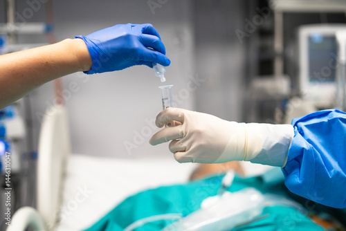 Medical professionals preparing medication in operating room during surgery