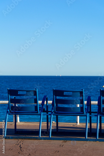 Les emblématiques chaises bleues de la Promenade des Anglais à Nice, alignées face à la mer Méditerranée, par une journée ensoleillée du printemps 2017. Un symbole du littoral niçois !