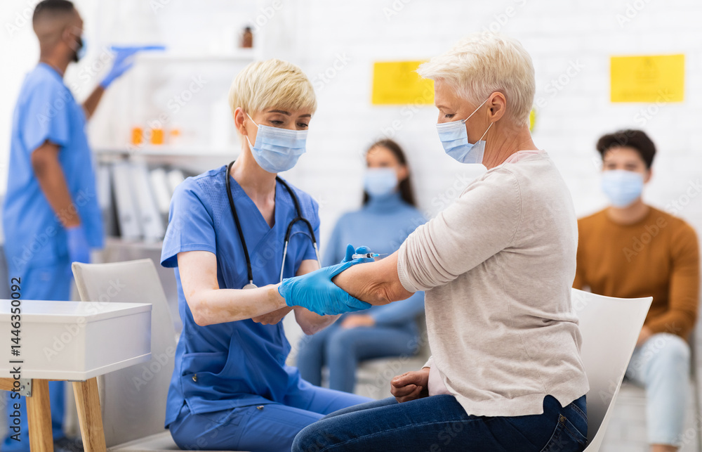 Obraz premium Covid-19 Vaccination. Senior Patient Lady Getting Vaccinated Against Coronavirus Sitting With Doctor In Hospital, Wearing Face Mask. Nurse Injecting Corona Virus Vaccine Shot To Older Woman