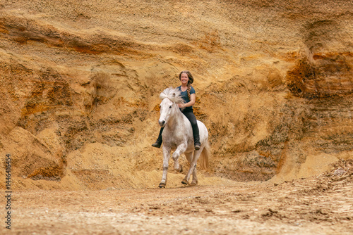 Obraz na płótnie A young woman and her white icelandic horse gelding interacting in a sand pit; horsemanship concept w salonie