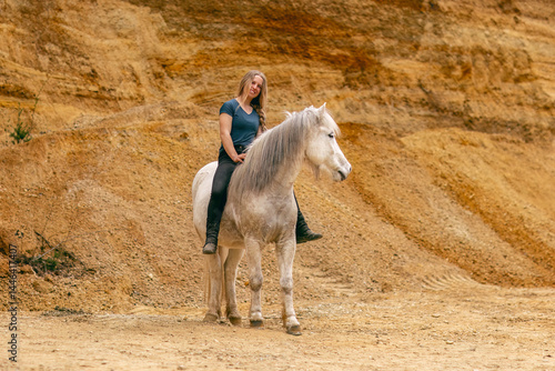 Obraz na płótnie A young woman and her white icelandic horse gelding interacting in a sand pit; horsemanship concept w salonie