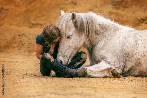 Obraz na płótnie A young woman and her white icelandic horse gelding interacting in a sand pit; horsemanship concept w salonie