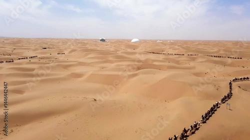 Epic camel caravan traverses the Tengger Desert in Zhongwei Ningxia against a backdrop of rolling sand dunes