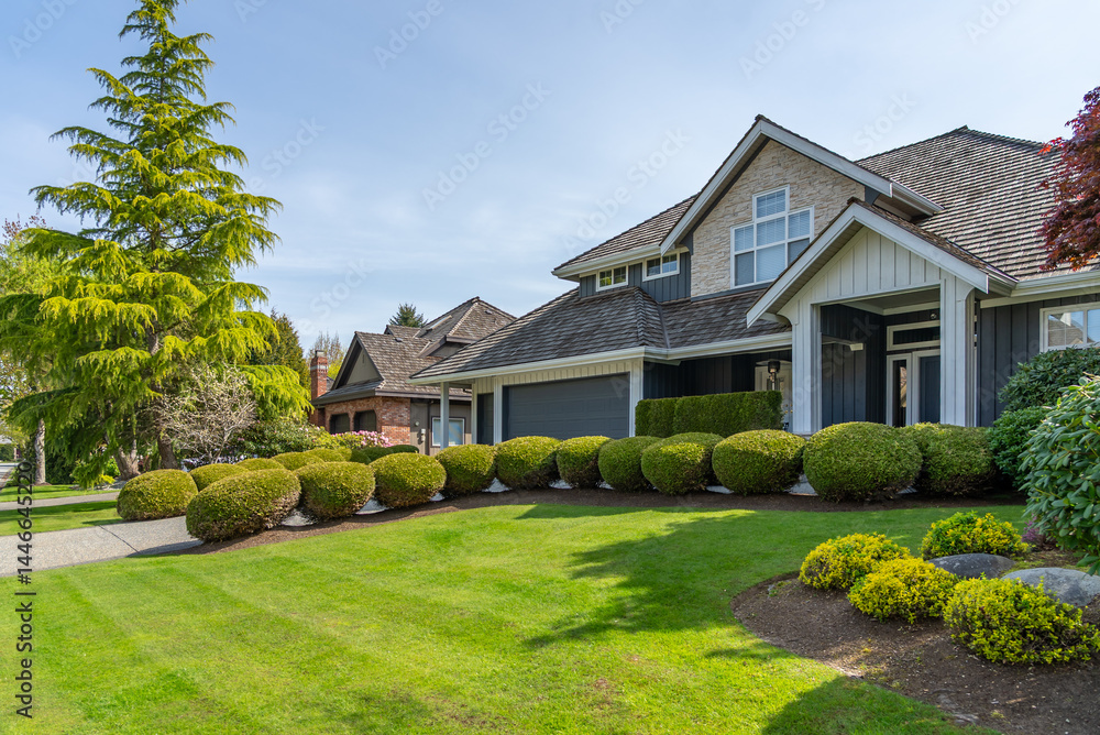 Fototapeta premium Two story stucco luxury house with nice spring blossom landscape in Vancouver, Canada, North America. Day time on April 2025.