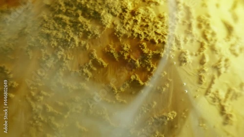 Sand paint. Watercolor fume. Dissolving powder yellow orange swirl pigment color defocused wall water abstract texture background.