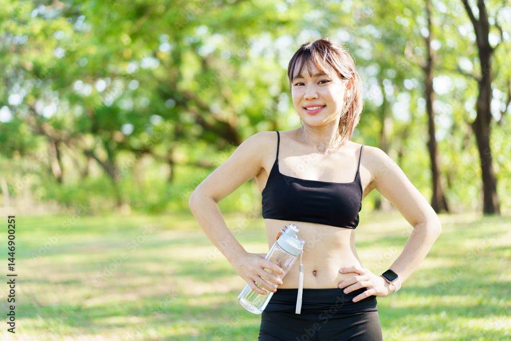 Fototapeta premium Asian woman take a break and drinks water from bottle after finished running.