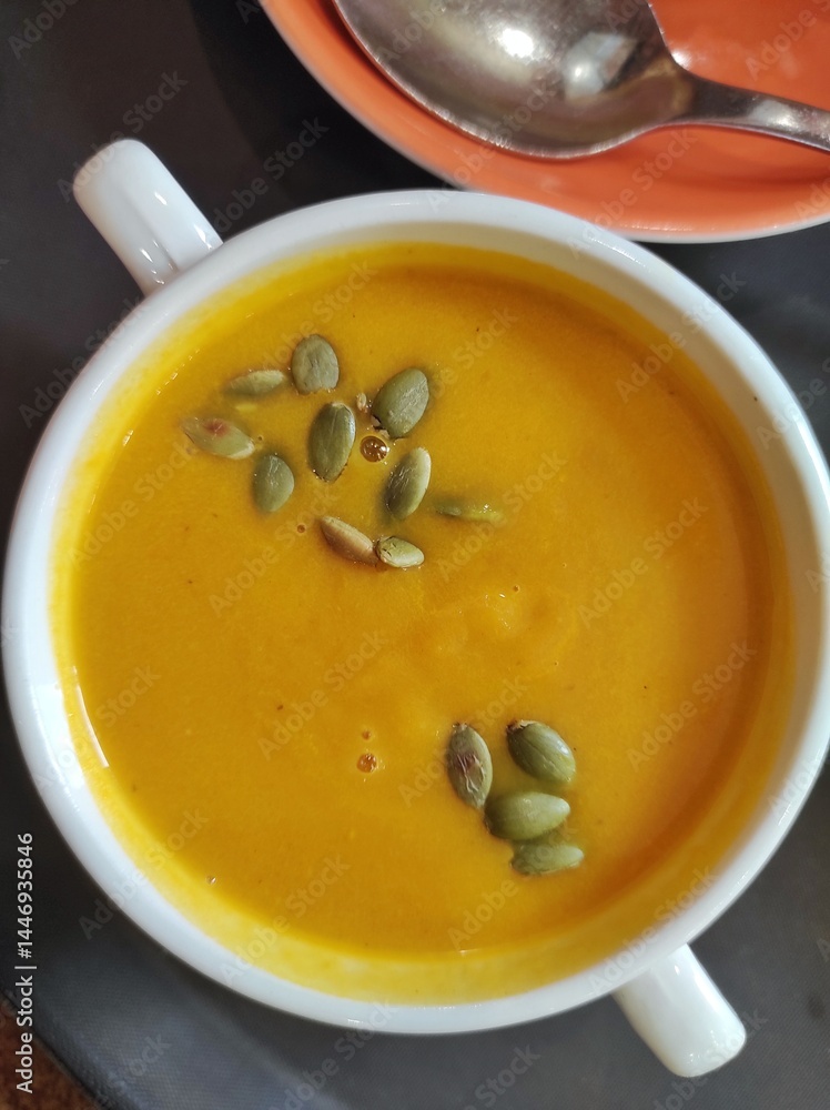 pumpkin soup in a white bowl, pumpkin seeds are poured from the top pumpkin soup in a white bowl, pumpkin seeds are poured from the top